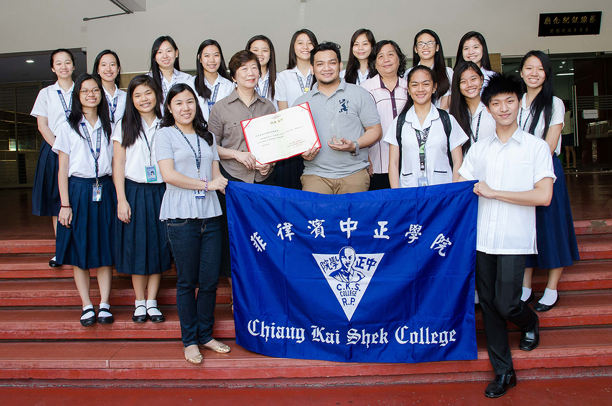 Dr. Poa and dance troupe head coach Marvin Ng hold up the award with pride; Janine Go and Shaun Lim display the Chiang Kai Shek College banner.